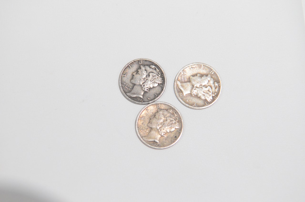 Three Mercury dimes recovered from the ground photographed on a light surface